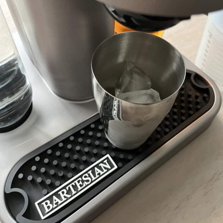 Cocktail shaker full of ice under dispenser