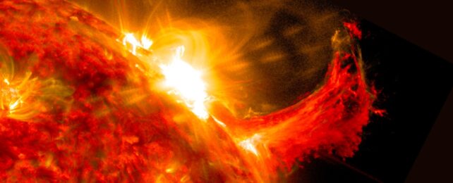 About a quarter of the sun with a solar flare seen as a bright flash of light at the top. A burst of solar material erupting out into space can be seen just to the right of it.
