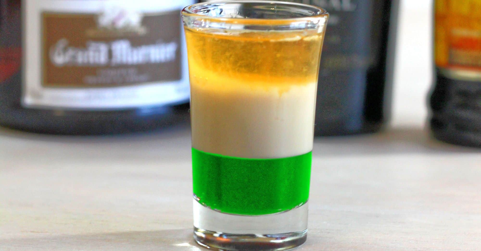 St. Patrick's Day cocktail on table in front of liquor bottles