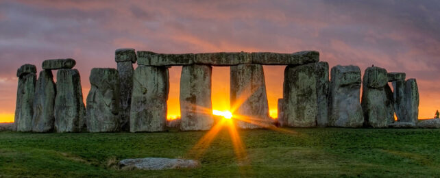 stonehenge with sunset seen though an arch