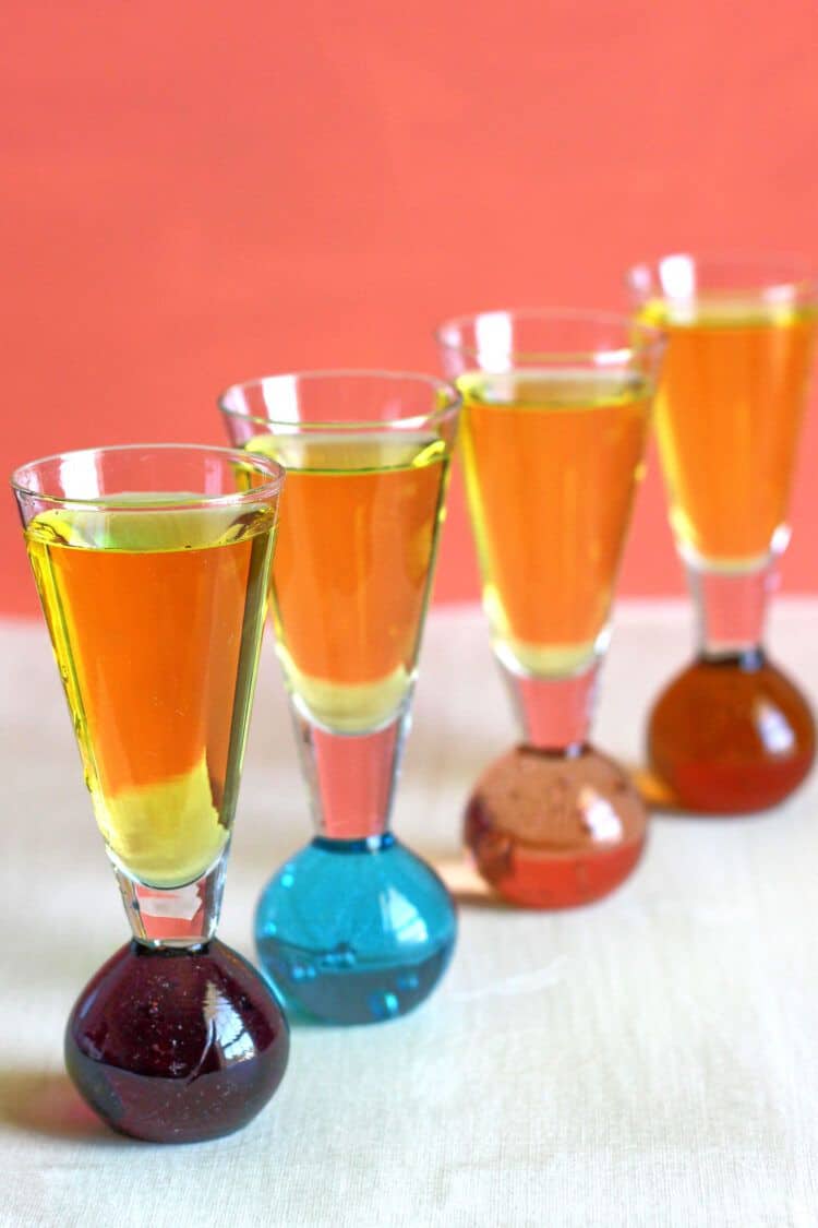 Four Sunny Mexico drinks lined up against an orange background