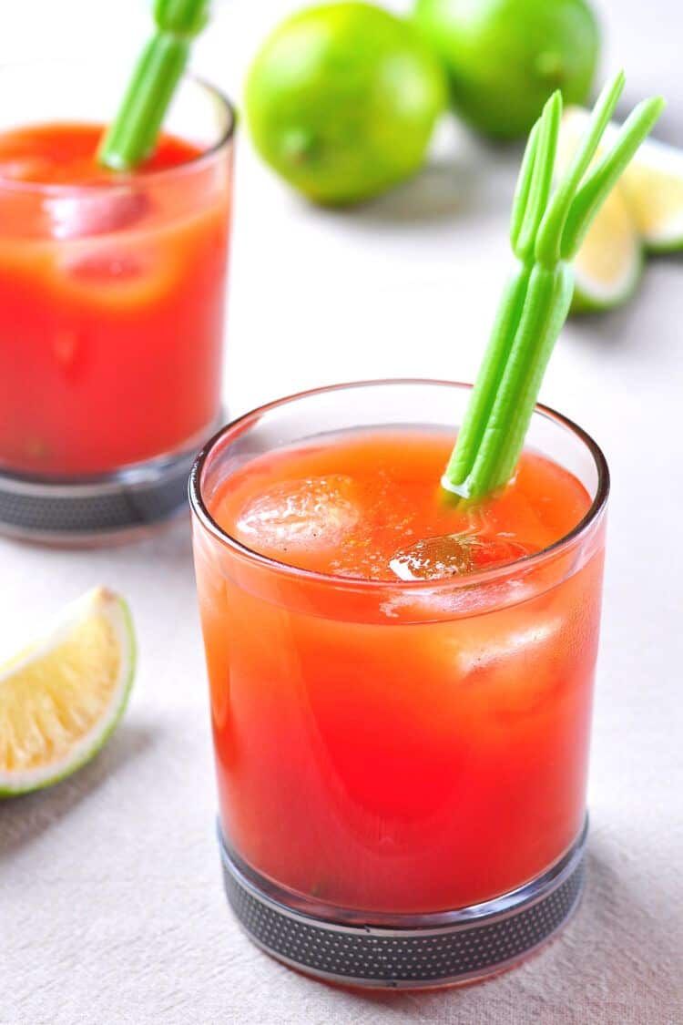 Two Virgin Mary mocktails with celery garnish and limes